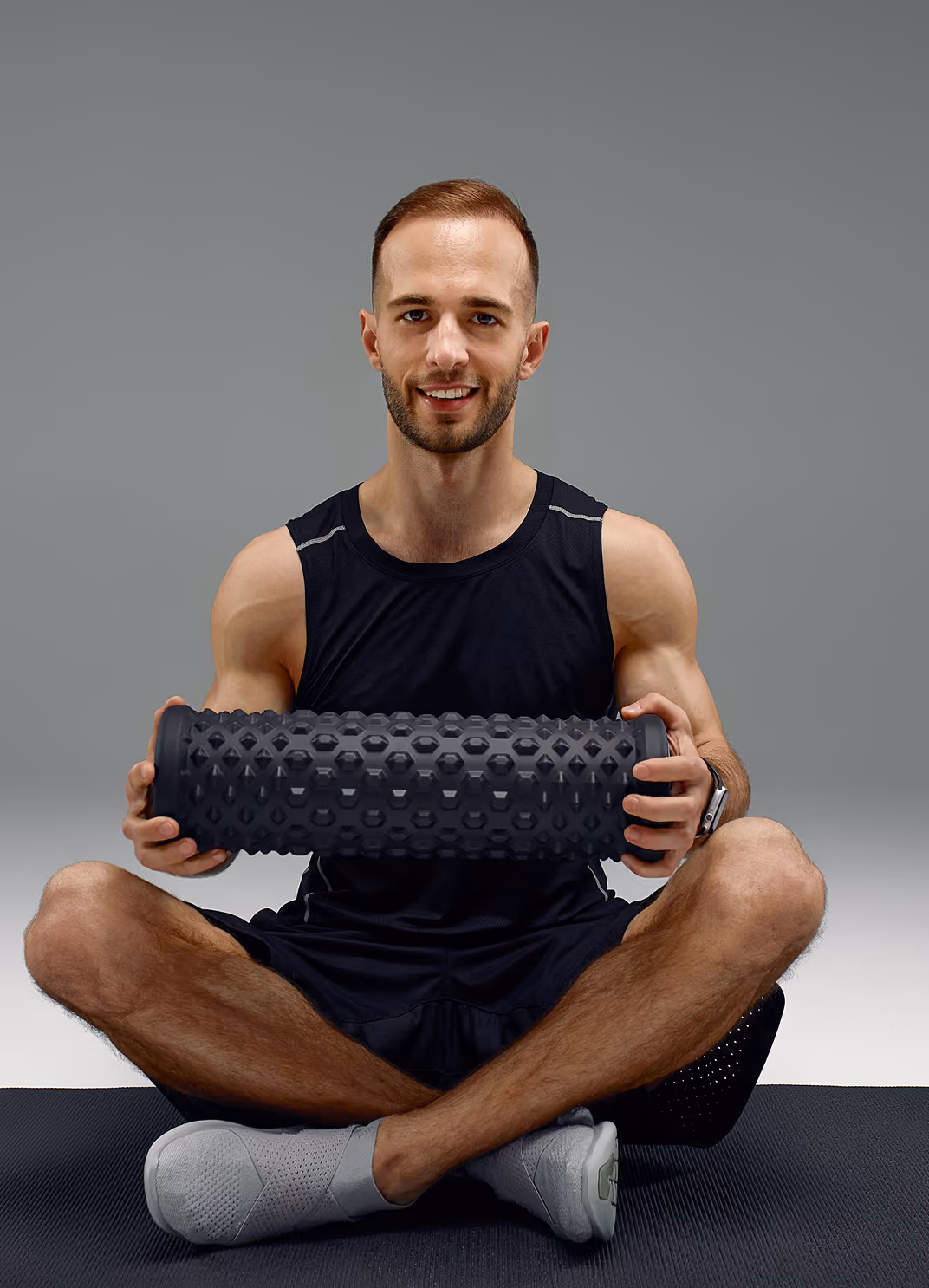 Man sitting on the floor holding a foam roller